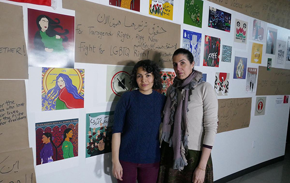 Ph.D. candidate Mona Moayedi and DU Professor Poupeh Missaghi stand in front of the #WomanLifeFreedom: Iran Today exhibit.