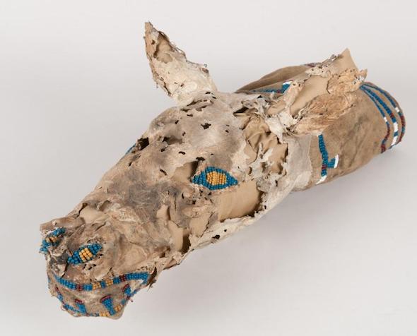 Photograph of a bag, made of fawn skin, shaped and decorated with beads to resemble a deer head.