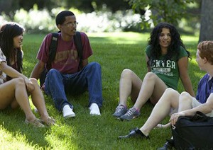 A commonly used campus stock photo shows four students of different skin tone sitting on the grass on campus