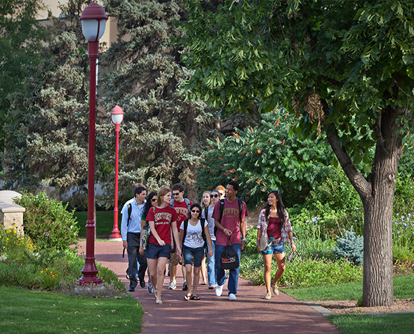 A group of students walks across campus behind the Mary Reed Building