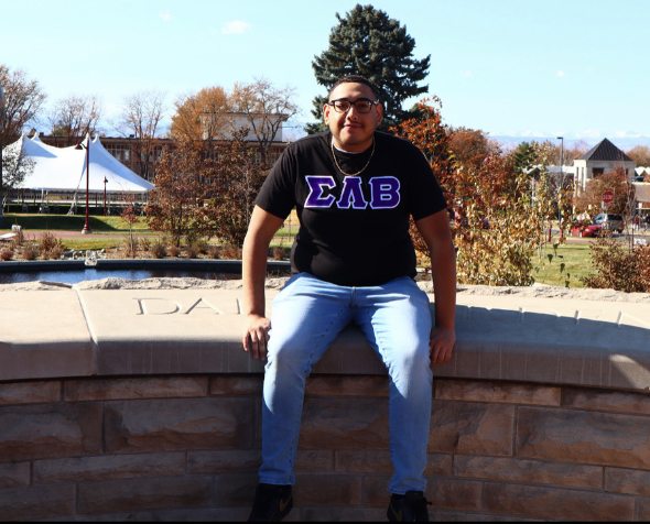 Student wearing a Sigma Lambda Beta shirt sits on the DU campus