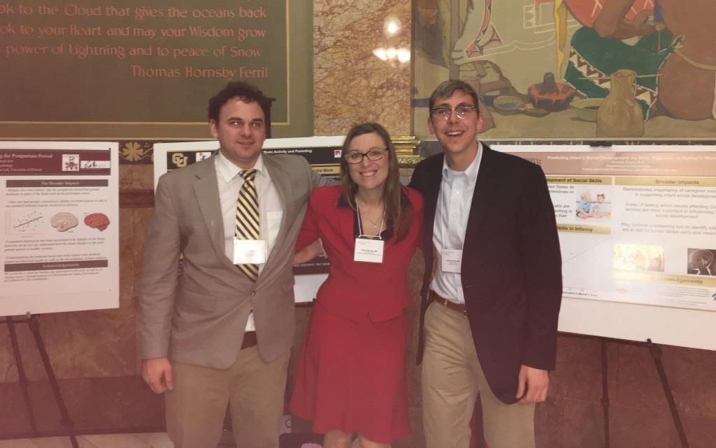 Three people stand in front of poster presentations