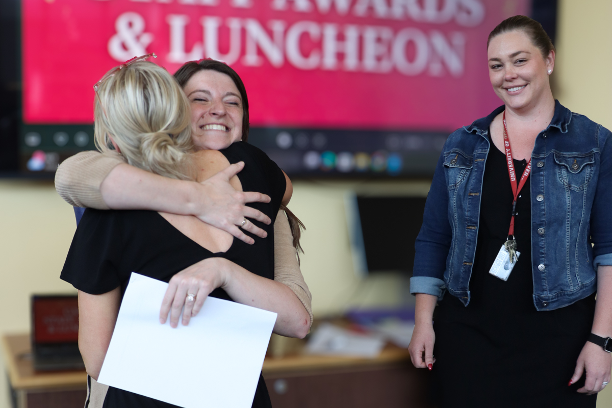 Recipient Amy Hilgers being hugged and celebrated by her coworkers as she wins an award.
