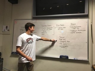 Strategic Communications student writing on a whiteboard
