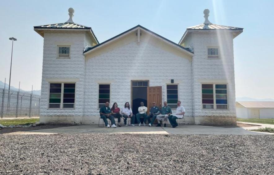 Members of the prison arts initiative sitting outside in front of a white building