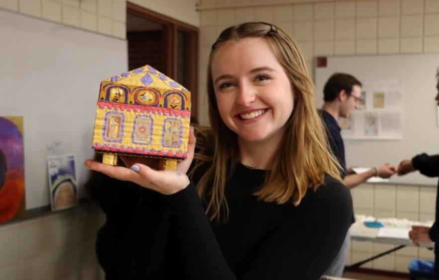 Student smiling and holding a small house