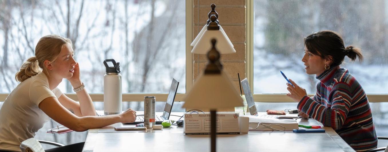 students talking at a table across from each other