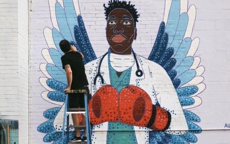 School of Art and Art History alumnus Austin Zucchini Fowler paints a mural honoring health care workers.