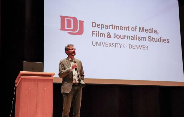 Faculty member speaking on stage into a mic