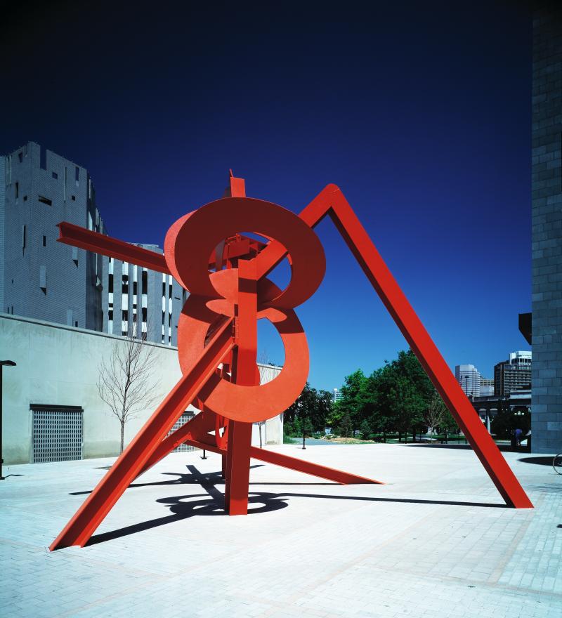 red painted steel abstract sculpture in front of a building