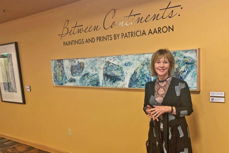 Patricia Aaron standing in front of the Between Continents exhibit.