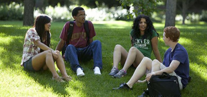 A commonly used campus stock photo shows four students of different skin tone sitting on the grass on campus