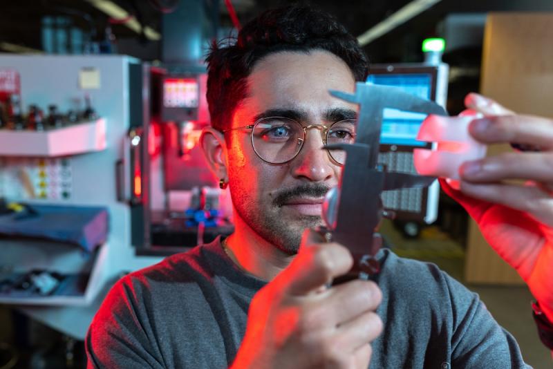 A graduate researcher in a lab uses a tool for measurement. 