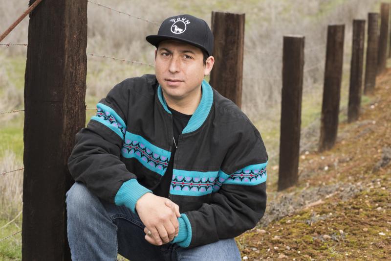 Photo of Tommy Orange outside beside a fence