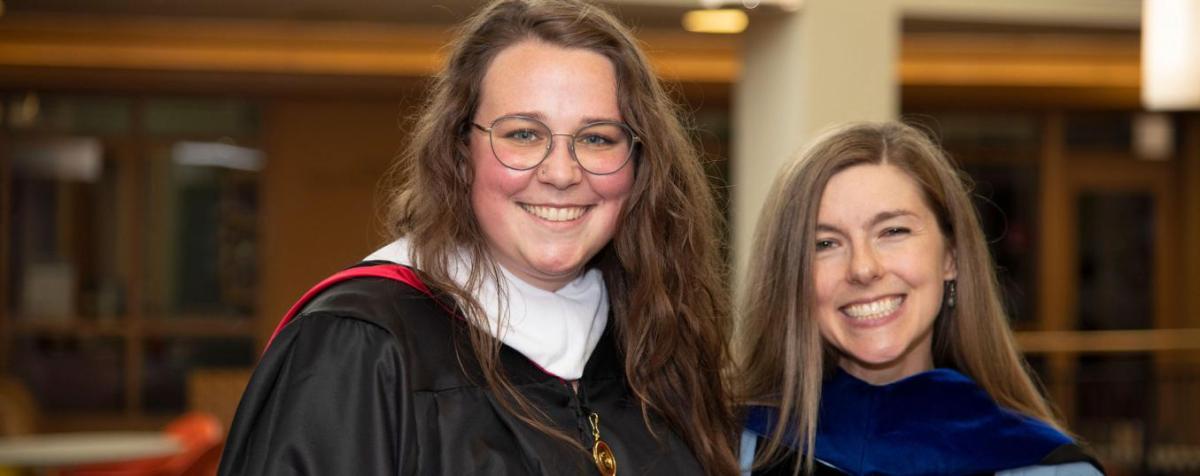 A political science student poses with her professor at graduation.