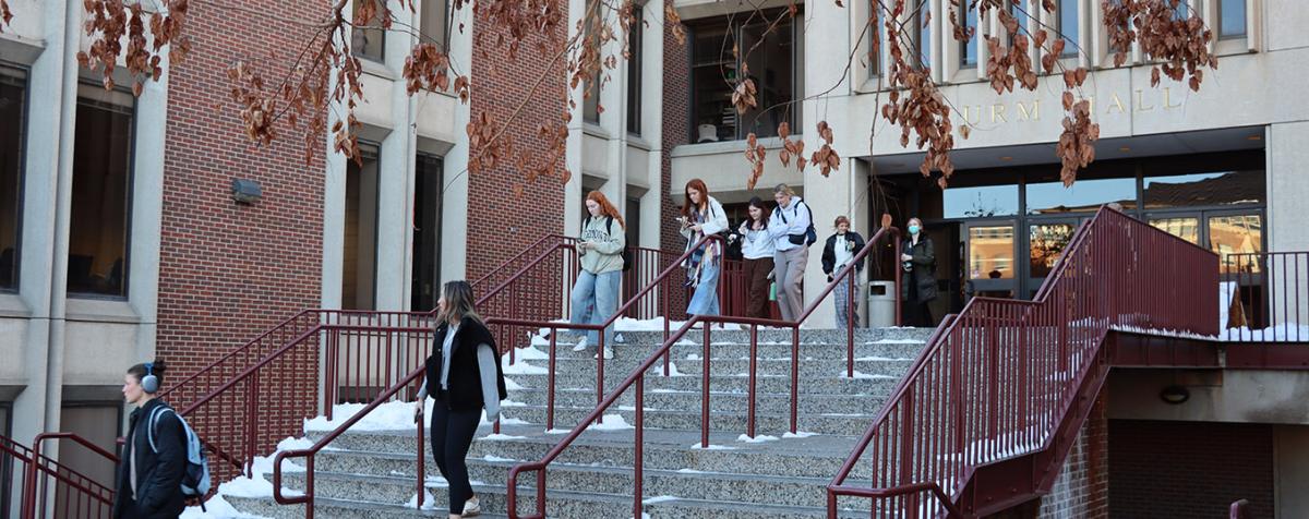 Students walking down the snowy steps outside Sturm Hall in the Winter.