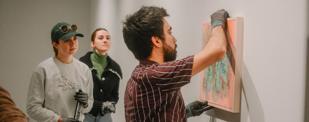 Art history graduate students hang paintings in the Davis Gallery