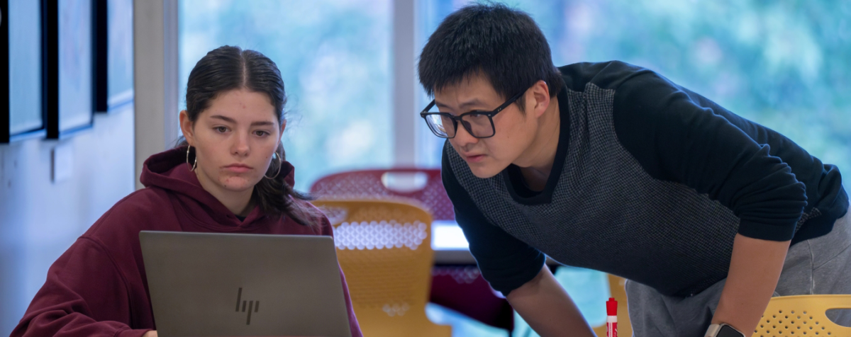 students chatting and looking at a laptop