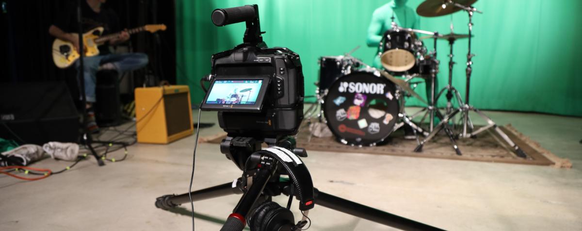 Students capture footage of a band playing against a green screen for a video project.