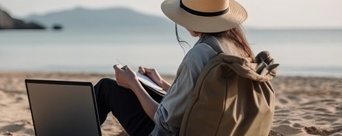 A woman sits on a beach with her computer.
