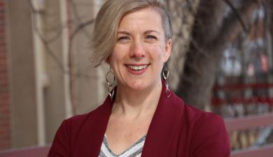 A woman smiles at the camera outside.