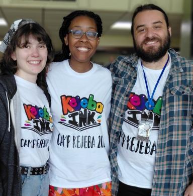 Three humans stand together smiling at the camera.