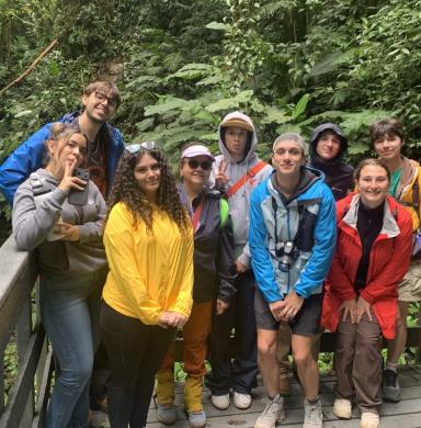 Students stand near a waterfall posing for the camera.