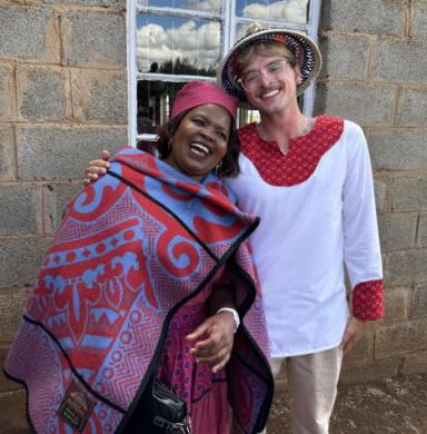 Two people stand together smiling. 