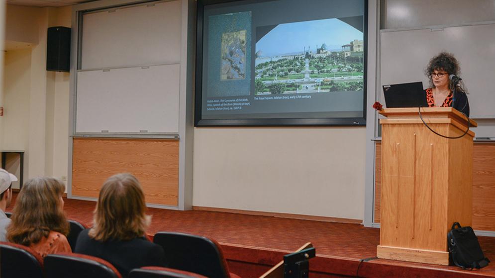 woman at podium giving lecture to seated audience