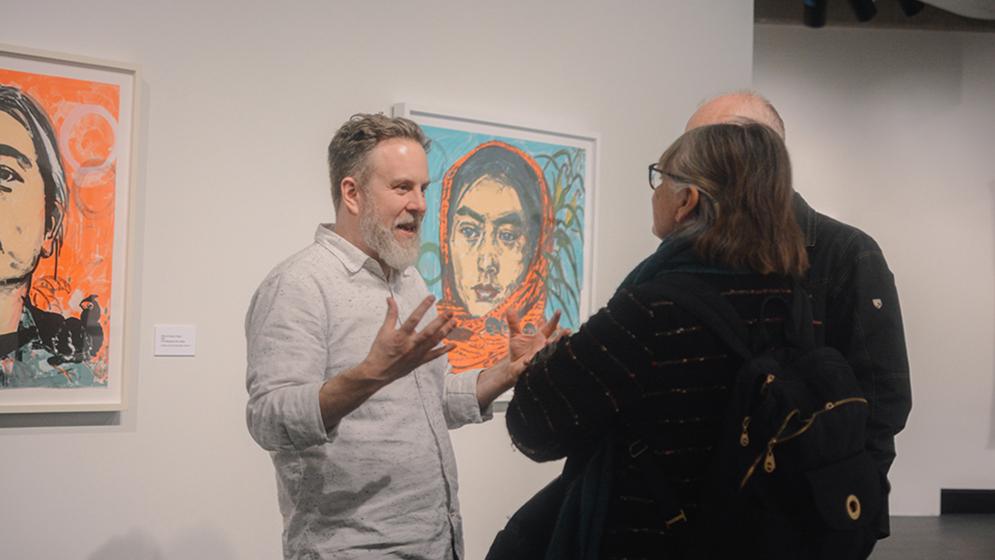 man and woman conversing in front of painting